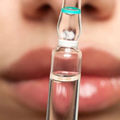 Ampulle vor Lippen – Symbolbild zur Lippenbehandlung